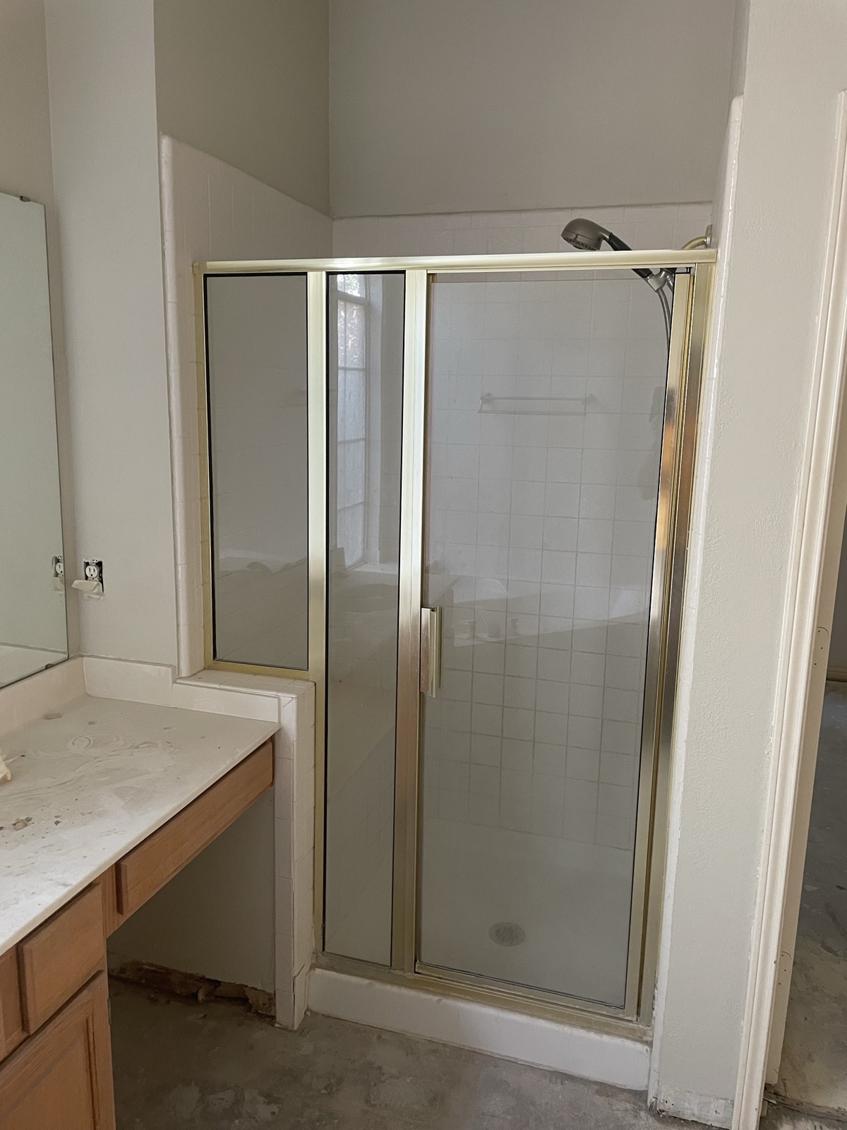 Dated bathroom with gold-framed shower enclosure before demolition