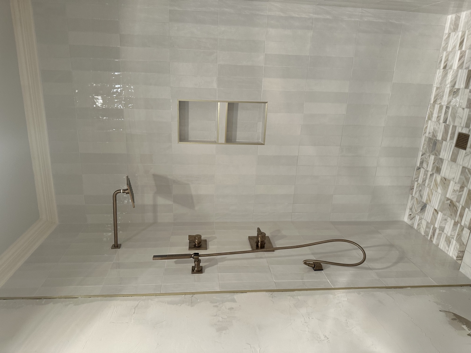 Tiled shower with brushed-bronze rain head, handheld sprayer, and dual niches
