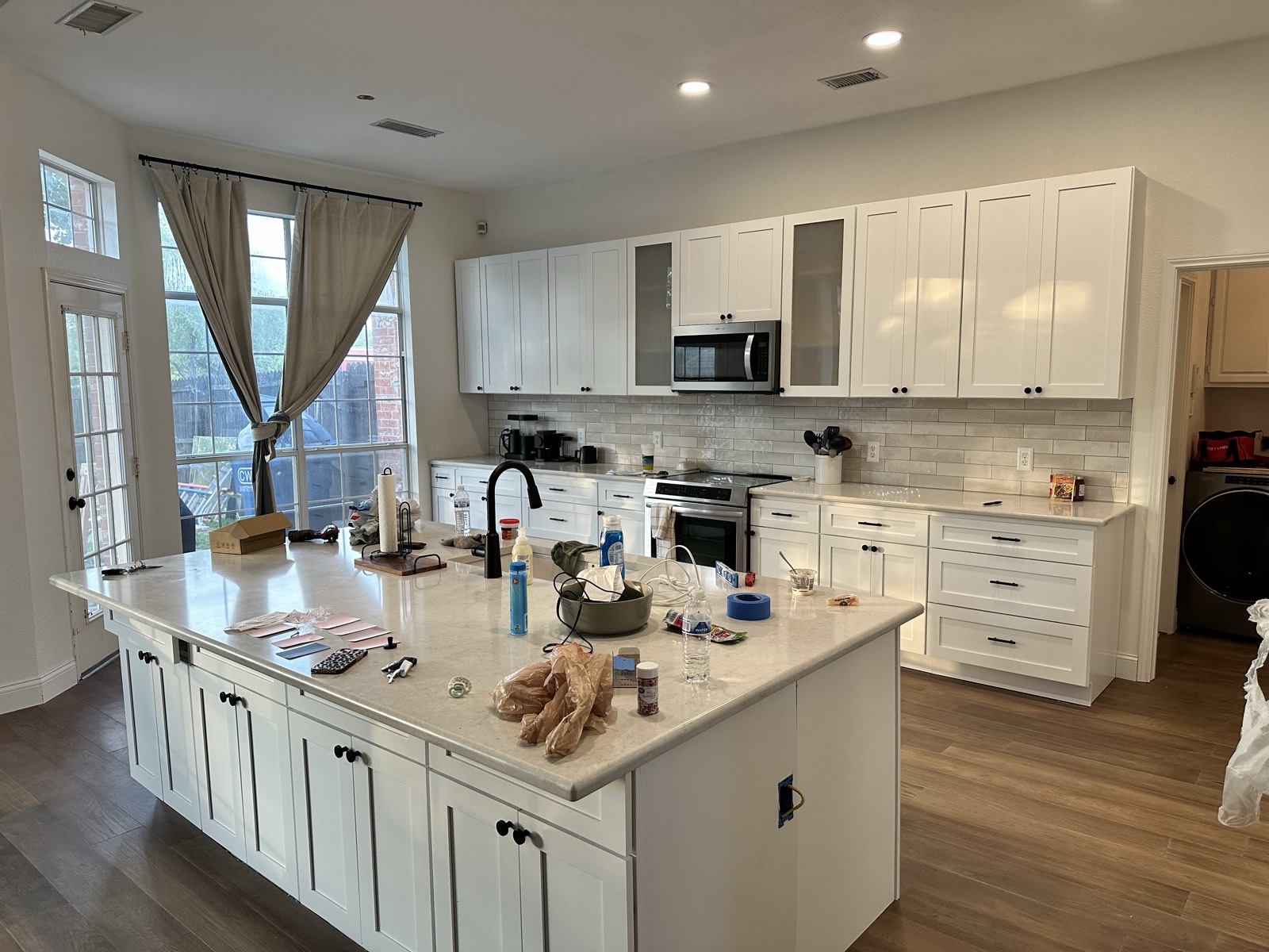 Finished kitchen with white shaker cabinets, quartz island, and subway tile backsplash