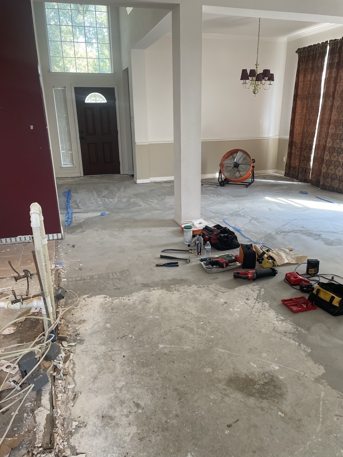 Gutted entry and living area with flooring removed during demolition