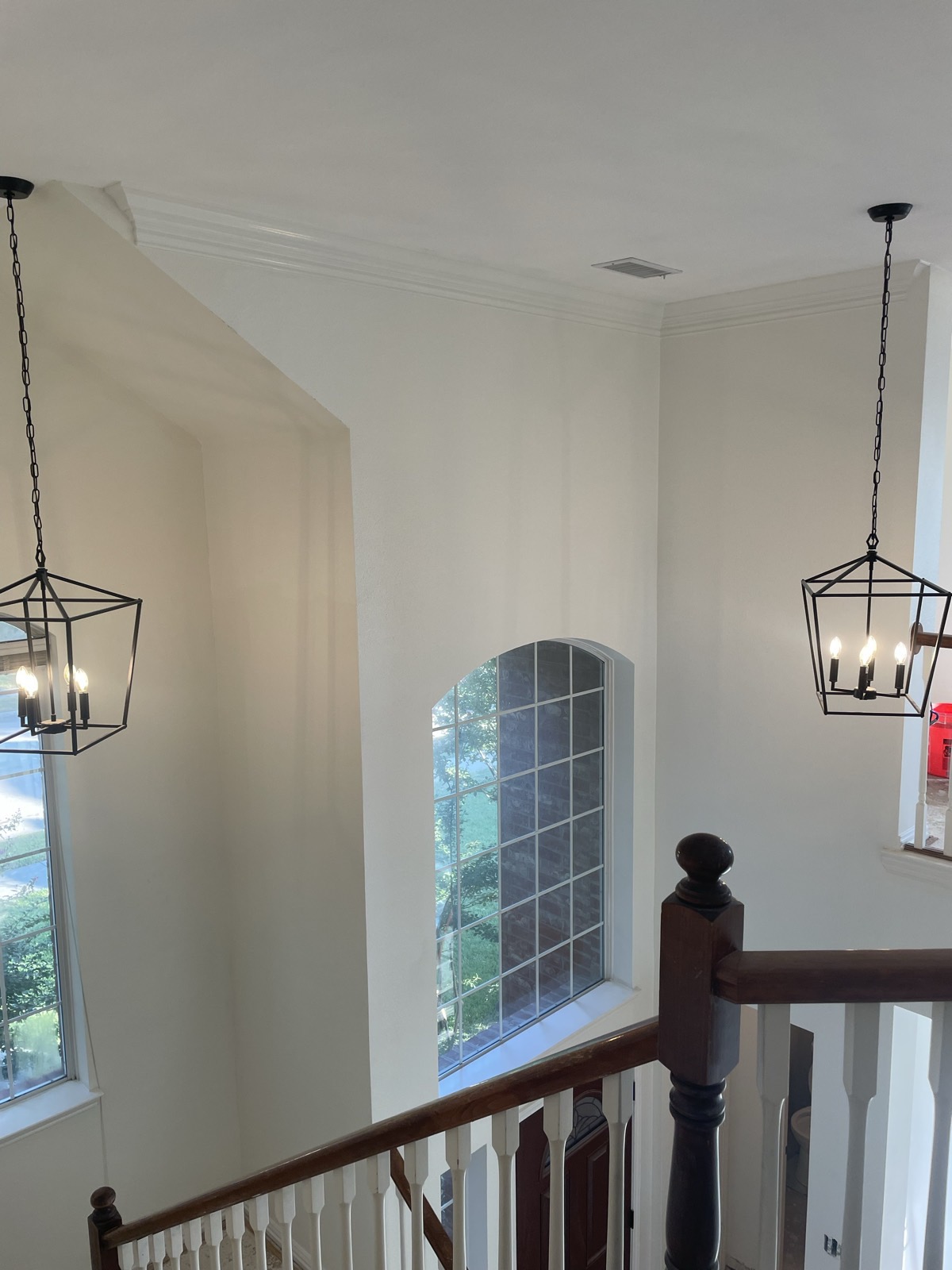 Two-story foyer with twin lantern pendants over the stairwell and arched window